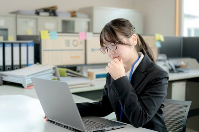 オフィスで考え込む若い女性社員